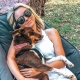 Smiling camper relaxing in a chair with a sleeping kelpie in her arms